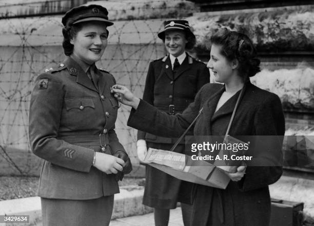 In ATS uniform, Mary Churchill , daughter of Winston Churchill buys a flag from Nurse Grover of University College Hospital.