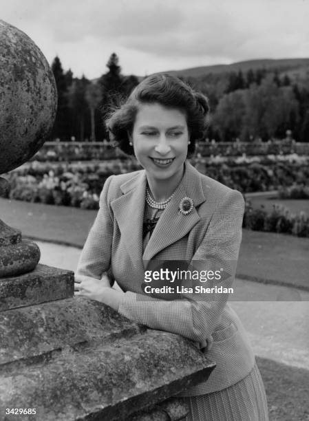 Queen Elizabeth II leaning on a stone wall in the grounds of Balmoral Castle. Balmoral is near Ballater on the River Dee in Aberdeenshire. Queen...