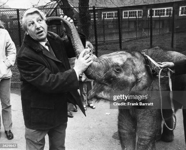 British television presenter, Johnny Morris, best known for his show 'Animal Magic', with Anna, a baby Elephant at London Zoo.
