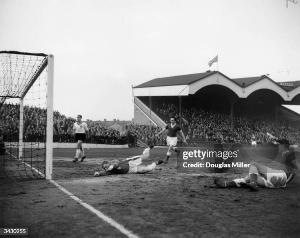 Charlton Athletic player John Hewie scores against Liverpool goalkeeper Young during a match at Charlton's Valley ground.