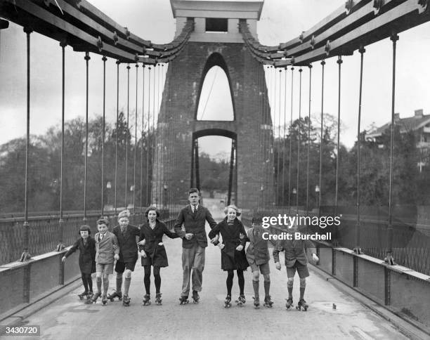 Group of schoolchildren rollerskating along the Clifton Suspension Bridge near Bristol.