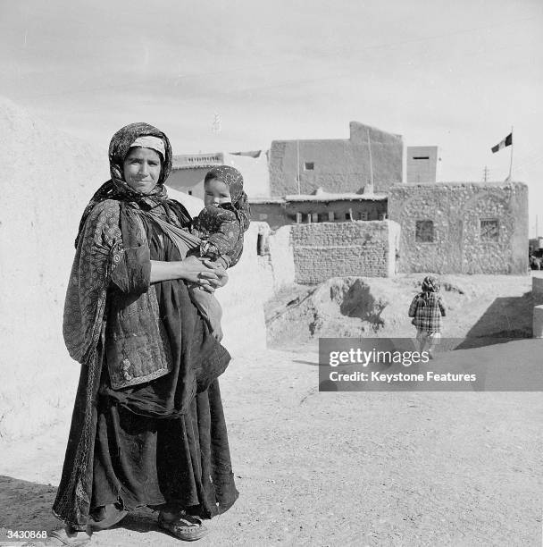 Kurd woman carries her child through a village street.