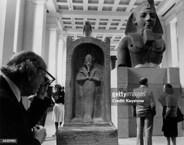Visitors inspect a large bust of Pharaoh Ramses II and a figure of the god Osiris in a limestone shrine, just two of the exhibits at the...