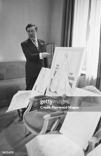 Couturier Norman Hartnell with his design for the Queen's coronation dress, 1953 . Original Publication: Picture Post - 6540 - Under The Red Robe -...