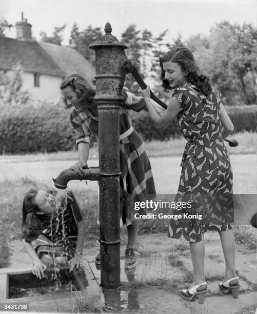 Rank starlets using the water pump at Ugley in Hertfordshire. Left to right - Sally Anne Howes, Jacqueline Martel, Zena Marshall.