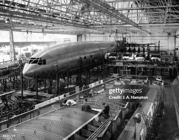 Work in progress in the erecting hangar of the world's biggest air liner, the Brabazon I. In the foreground men are at work on part of the giant...