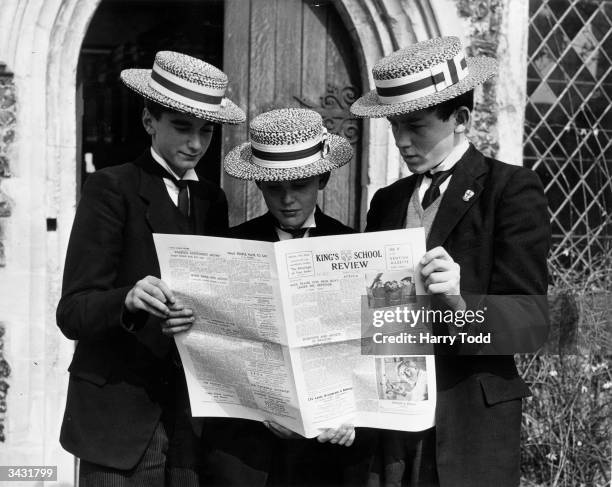 Three boys from Kings School, Canterbury, reading the school paper.