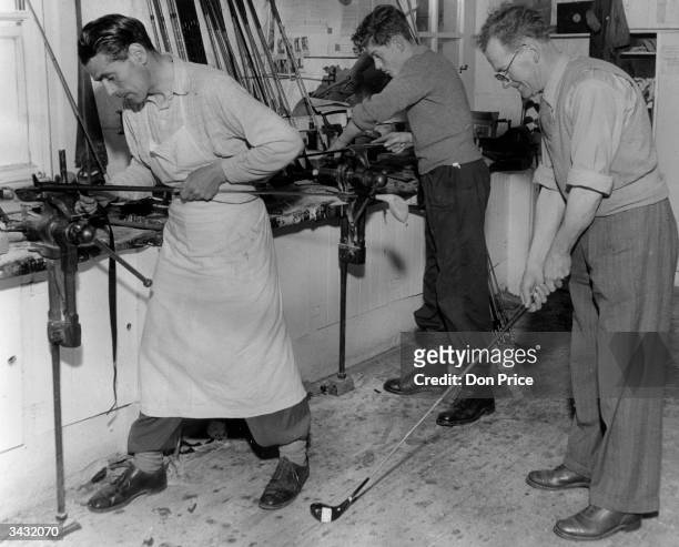 Mr Robertson, the manager of Tom Morris's workshop in St Andrews, tests a golf club for balance while two men work on new clubs.