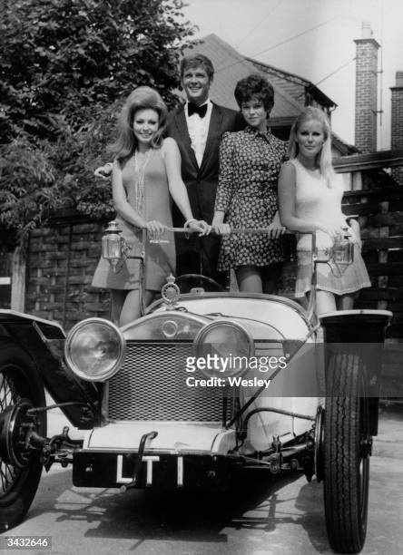 Film star Roger Moore ex star of the TV series 'The Saint' aboard a car made specially for his new film, 'Crossplot'. With him are his co-stars, l to...