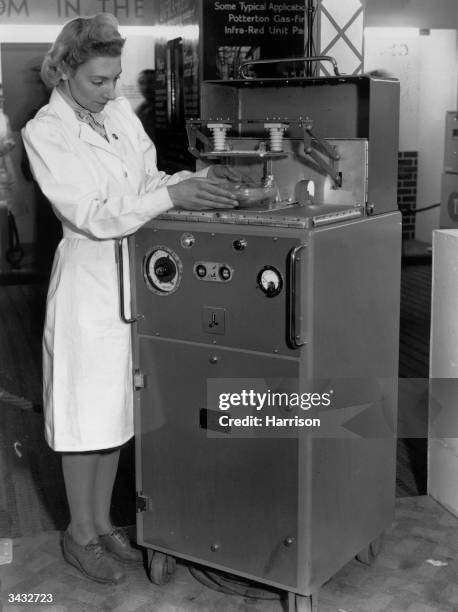 Woman using a 'Radio Frequency Heater' - an early microwave made by the British company, EMI, at the Ideal Home Exhibition at Olympia, London, 5th...