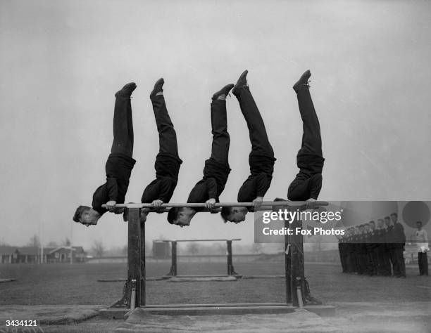 Soldiers doing handstands on parallel bars at the Army Physical Training School, Aldershot, Hampshire.