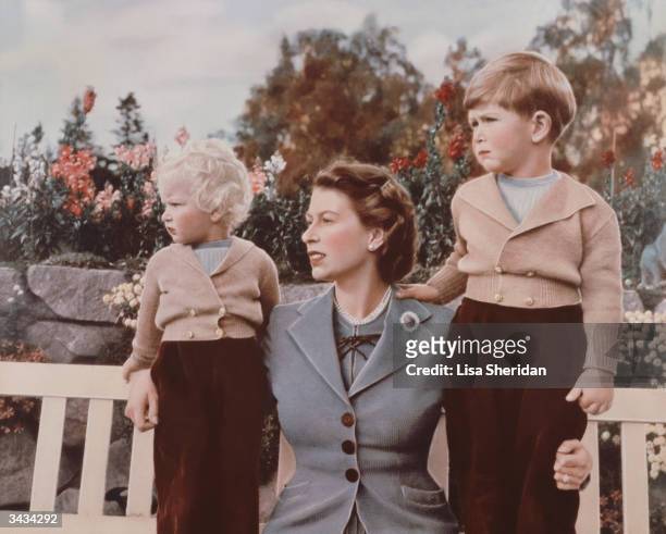 Queen Elizabeth II with Prince Charles and Princess Anne in the grounds of Balmoral Castle, Scotland. Charles is celebrating his 4th birthday.