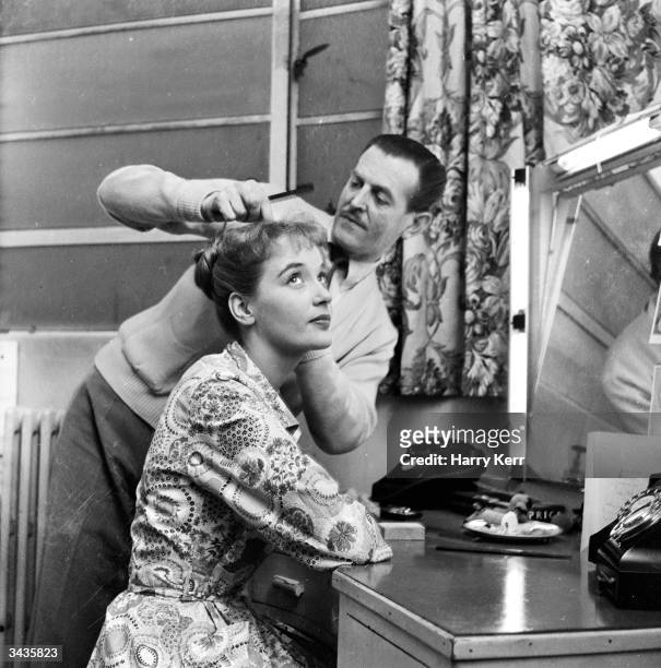 English actress Sylvia Syms is visited by the hairdresser whilst filming 'No Time for Tears' at Elstree Studios, Hertfordshire.
