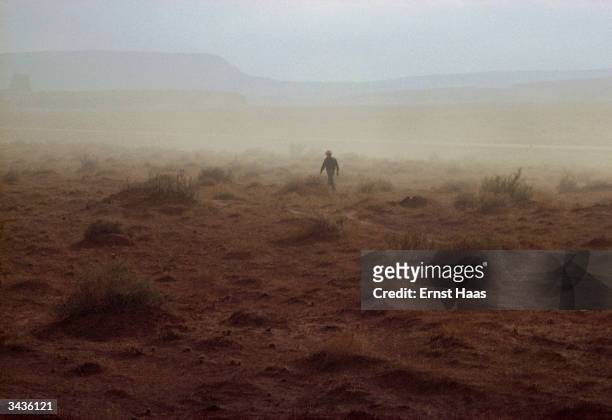 An American Indian walks through the yellow landscape of a Nevada duststorm.