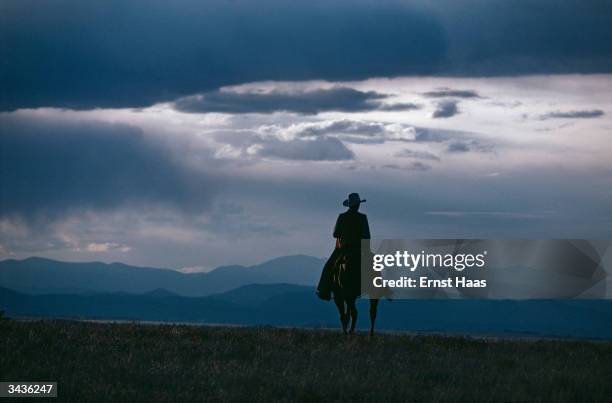 Colorado cowboy silhouetted against mountains and a lowering sky.