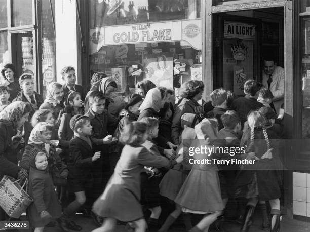 Crowd of children rush to get into a sweetshop in north Acton as it opens its doors on the day sweet rationing ended.