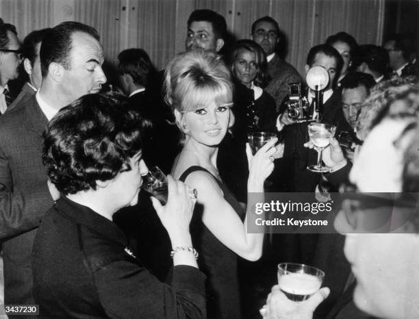 French film star Brigitte Bardot raises her glass at a press conference for Jean-Luc Godard's latest film, 'Le Mepris' .