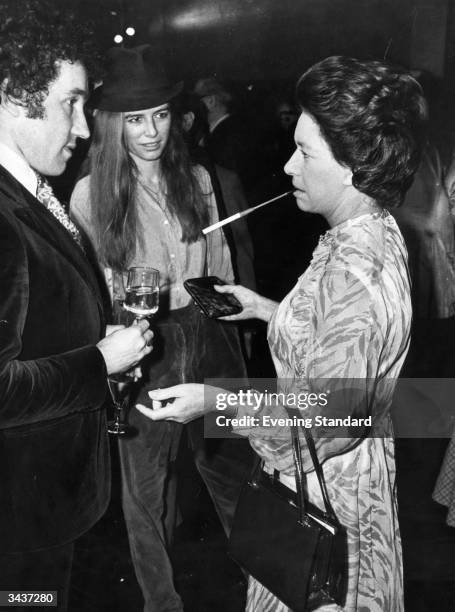 With a long cigarette holder Princess Margaret Rose , younger daughter of King George VI and Queen Elizabeth and sister of Queen Elizabeth II talks...