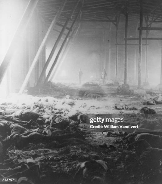 Soldiers survey the scene in a barn in Germany, after an undetermined number of political prisoners were gunned down and burnt by their German...