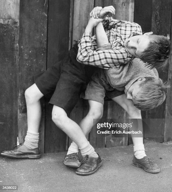 Two young boys wrestling in fun, one has the other in an arm-lock.