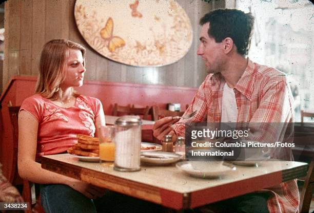 American actors Jodie Foster and Robert De Niro sit together at a diner in a still from the film, 'Taxi Driver' directed by Martin Scorsese.