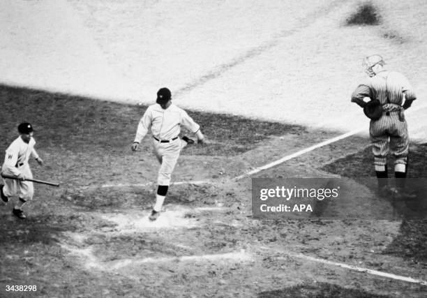 American baseball player Stanley 'Bucky' Harris , playing for the Washington Senators, lands on home plate after scoring a homerun during the seventh...