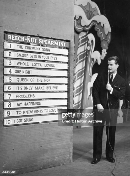 American TV show host Dick Clark anounces the week's top ten popular songs during an episode of the television program, 'American Bandstand.'