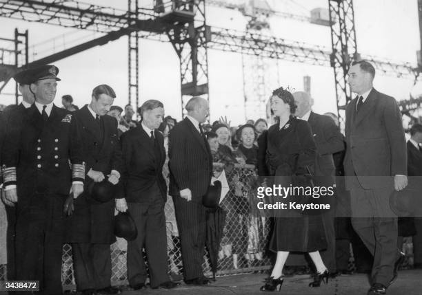 Queen Elizabeth II on her way to perform the launching ceremony of the new Royal Yacht Britannia at the John Brown shipyard, Clydebank. On her right...