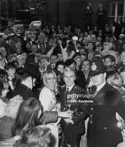 Pop singer and actor Adam Faith with his wife Jackie Irving surrounded by fans and police after their wedding at Caxton Hall registry office in...