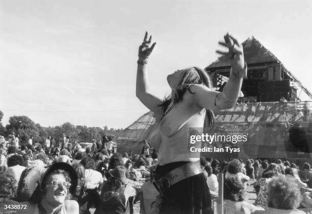 Young woman dances topless in front of the pyramid stage at the second Glastonbury fayre, organised by Arabella Churchill and Andrew Kerr at Worthy...