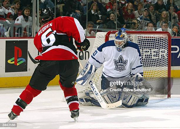 Goalie Ed Belfour of the Toronto Maple Leafs makes a save on Wade Redden of the Ottawa Senators during game six of the Eastern Conference...