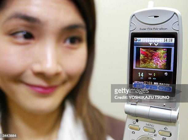 Japan's electronics giant Toshiba employee Midori Suzuki displays Vodafone's new handset "V401T", produced by Toshiba, which features a built-in TV...