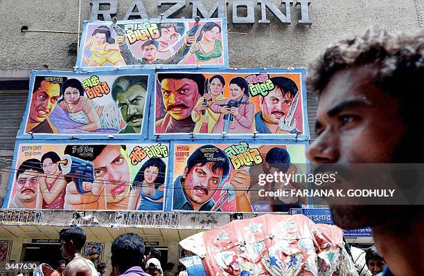 In this picture taken, 13 April 2004, a Bangladeshi man passes a cinema wall festooned with advertisements for current screenings in Dhaka. Popularly...