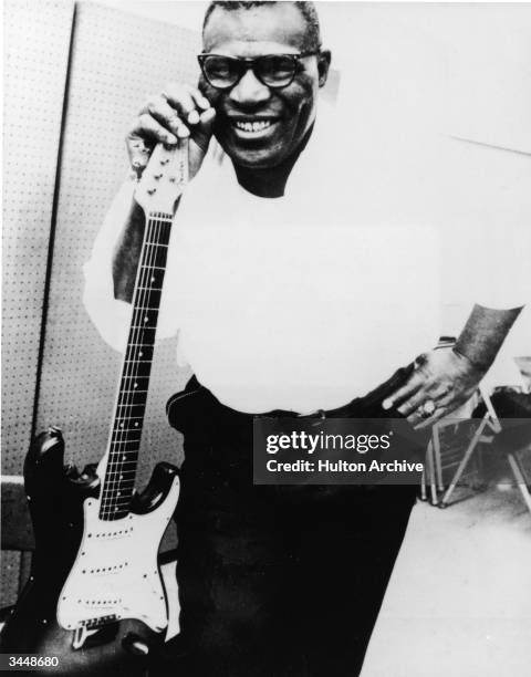 Portrait of American blues singer and songwriter Howlin' Wolf smiling beside an electric guitar, 1960s.