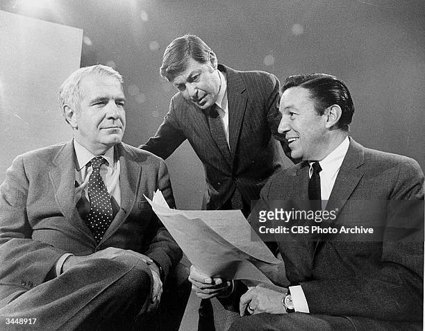 American broadcast journalists Harry Reasoner and Mike Wallace of the news program '60 Minutes' confer with producer and creator of the show, Don...