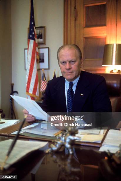 Portrait of House Minority Leader Gerald Ford as he sits at his desk and holds several papers, Washington DC, 1976.