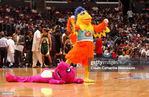 The Famous San Diego Chicken celebrates after knocking down Barney the Dinosaur during a break in the game between the Los Angeles Clippers and the...
