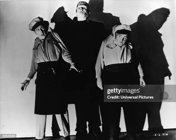 Frankenstein's monster lifts comedy team Bud Abbott and Lou Costello off the ground in a promotional still for the film, 'Abbott and Costello Meet...