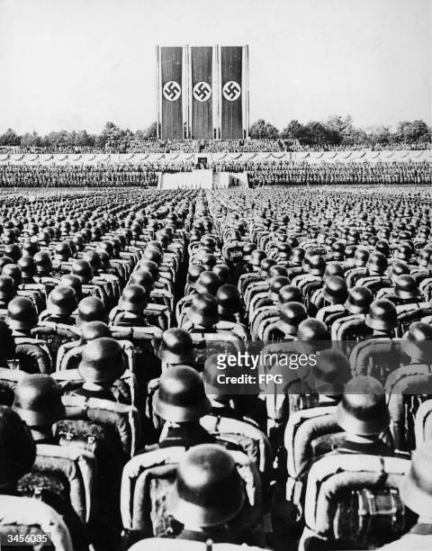 Massed troops stand at attention an dlisten to speeches during a Nazi rally in Nuremberg, Germany, September 1934. Among the speakers at the rally...