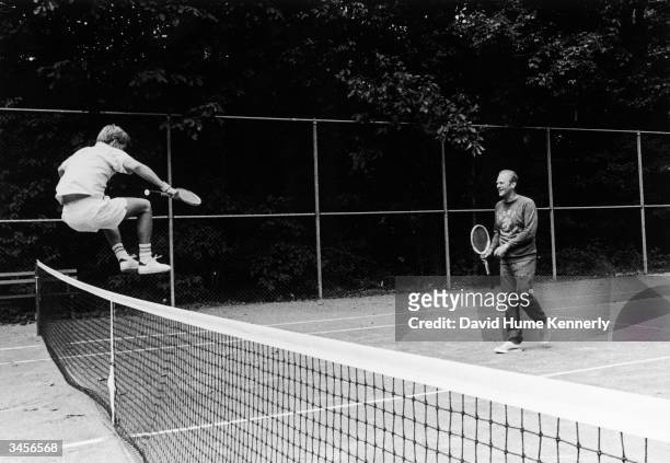 Steven Ford jumps over a net to congratulate his father, American President Gerald Ford after tennis match, Washington DC, 1974.