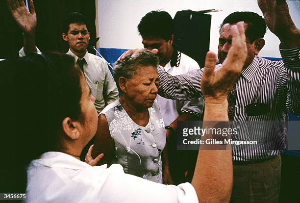 Worshipers asked for Jesus' help as they try to heal a women suffering from stomach pain at a storefront Pentecostal church March 15, 2003 in...