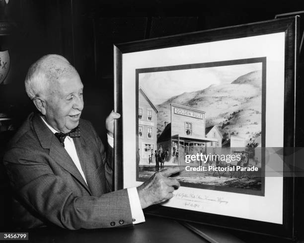 American businessman James Cash Penney , owner of the JC Penney chain of retail stores, points to a picture of his first store, Golden Rule, in...