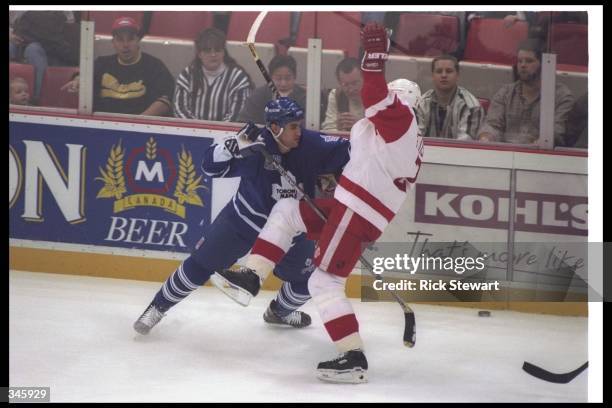 Defenseman Viacheslav Fetisov of the Detroit Red Wings and Matt Martin of the Toronto Maple Leafs tangle up during a game at Joe Louis Arena in...