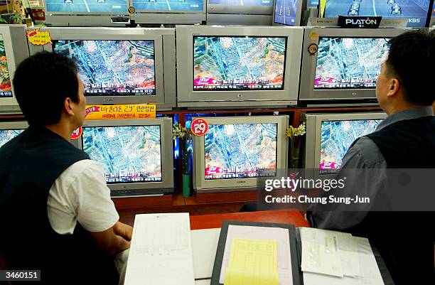 South Korean men watch a satellite photo of the train explosion in North Korea on televisions at an electronic department store on April 23, 2004 in...