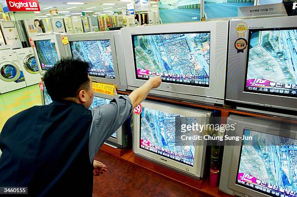 South Korean man watches a satellite photo of the train explosion in North Korea on televisions at an electronic department store on April 23, 2004...