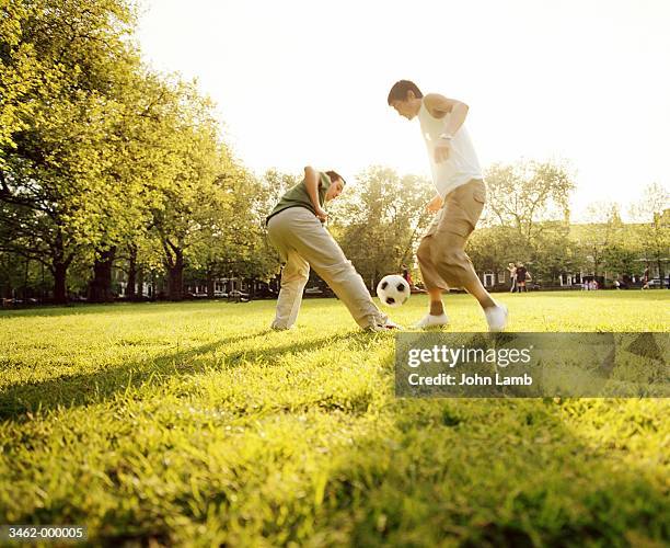 2 men playing football in park - public park stock pictures, royalty-free photos & images