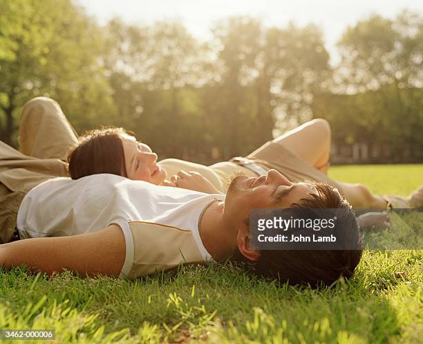 couple lying in park - lying down stockfoto's en -beelden
