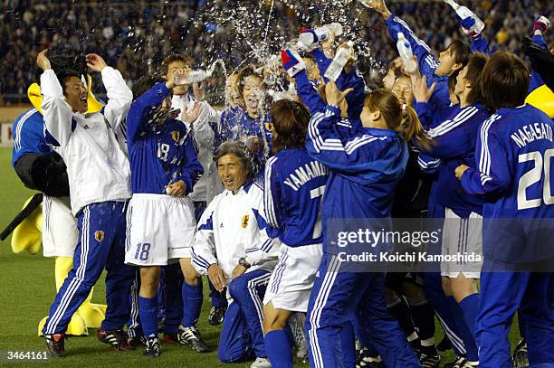 Members of the Japanese national women's soccer team, celebrate a victory over North Korea with Coach Eiji Ueda at the AFC Olympics qualifying...