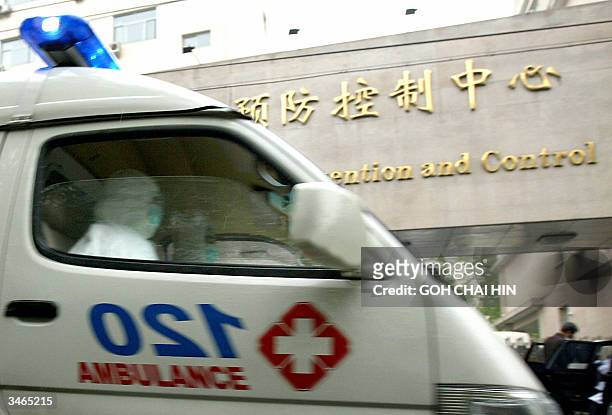 An ambulance with medical personnel in full protective gears, speeds pass the Center for Disease Prevention and Control in Beijing 25 April 2004....