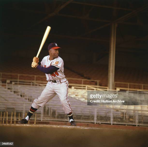 American baseball player Hank Aaron waits for the pitch in an empty stadium.